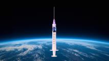 A syringe filled with liquid is suspended in front of a view of Earth from space, with the planet’s surface and atmosphere visible below.