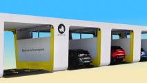 Several electric cars enter adjacent charging or battery-swapping stations under a white and yellow structure labeled "ample" with the slogan "Electric cars for everyone.