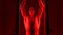 Man performing pull-ups under red lighting.